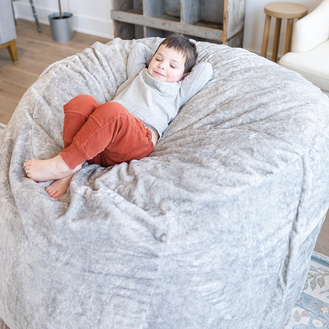 Child laying on Medium Haven foam filled bean bag in living room.