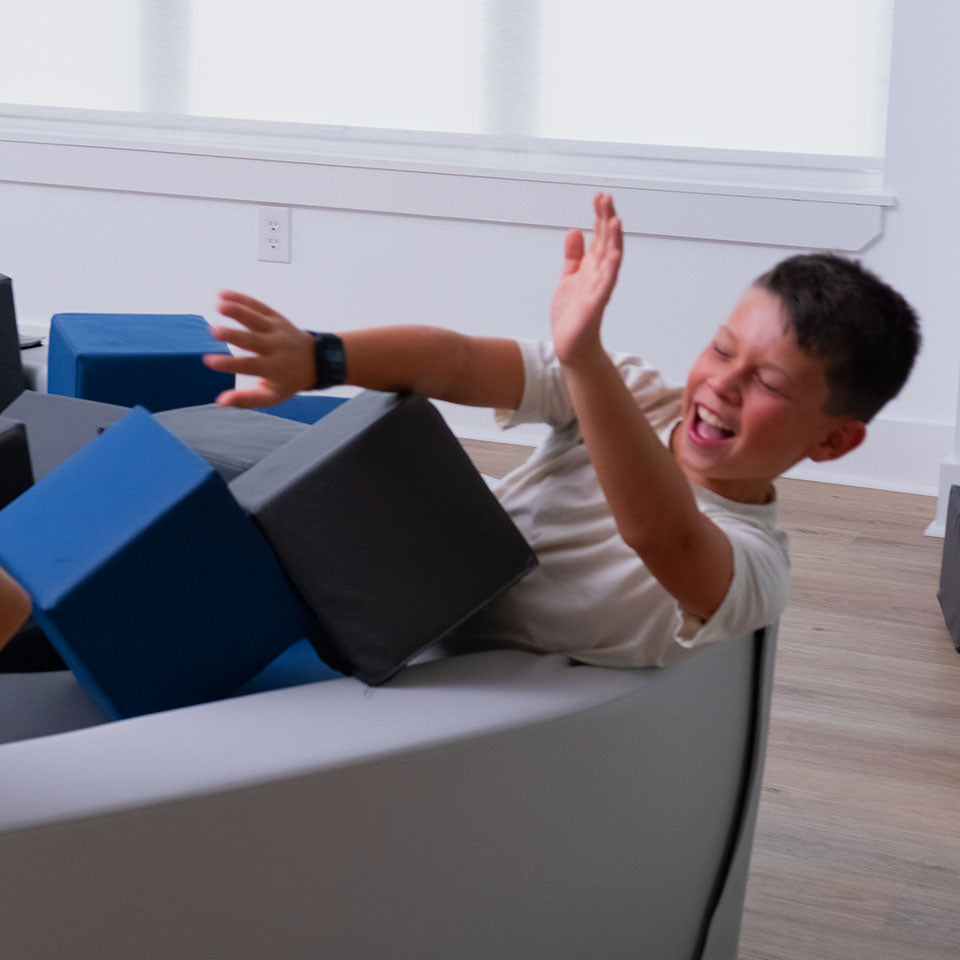 Child playing with foam blocks in a foam pit