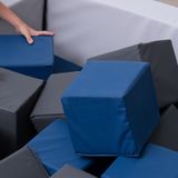 Person arranging blue and gray foam cubes in a foam pit
