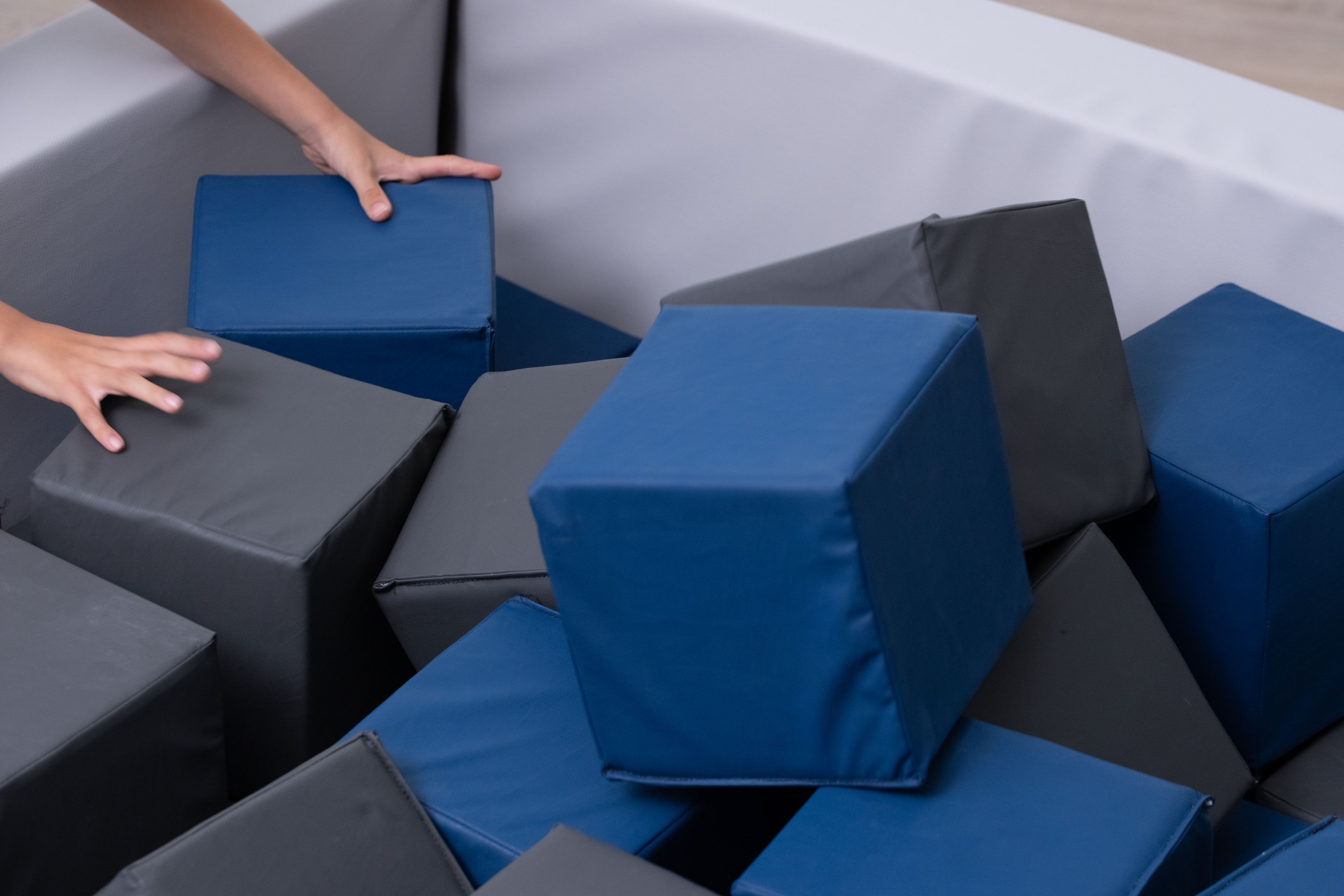 Person arranging blue and gray foam cubes in a foam pit