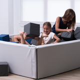 children playing with foam blocks on a foam pit in a room.