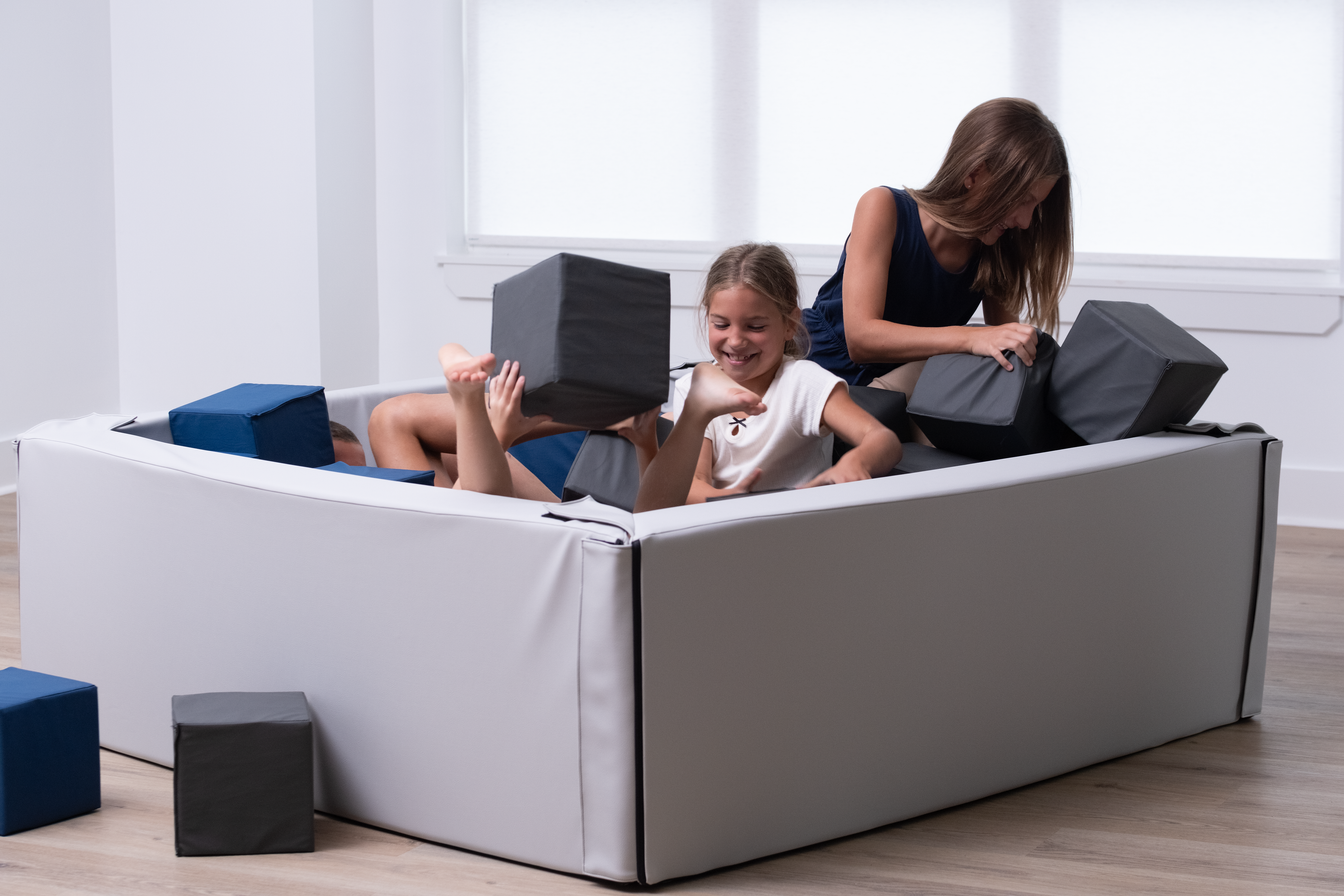 children playing with foam blocks on a foam pit in a room.