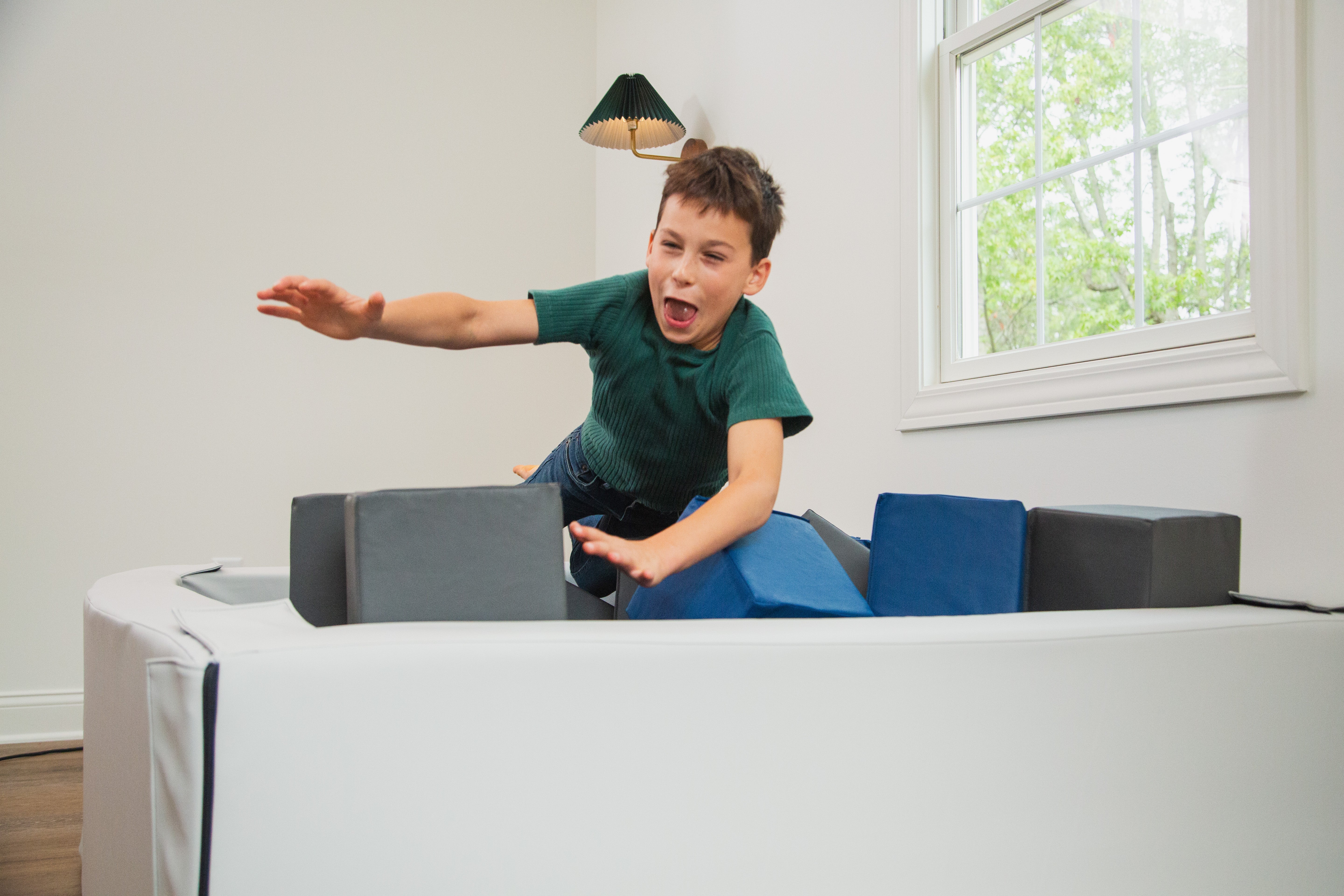 Child playing with foam blocks on a white surface in a room with a window.