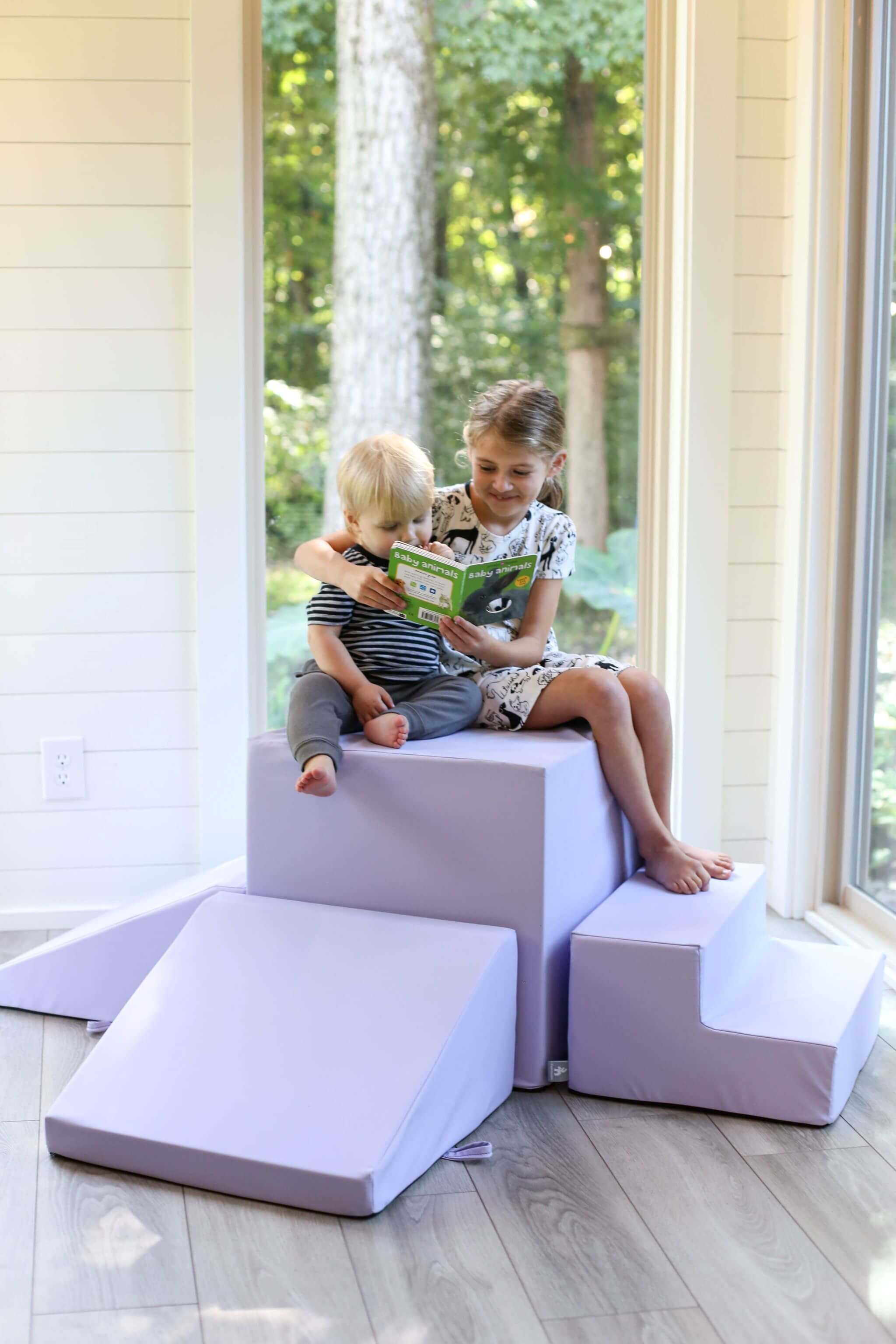 Lifestyle photo of a girl and a boy reading a book while sitting on a lavender gymnasium by Foamnasium