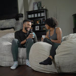 Two people sitting on Haven bean bags in a living room, holding coffee cups.