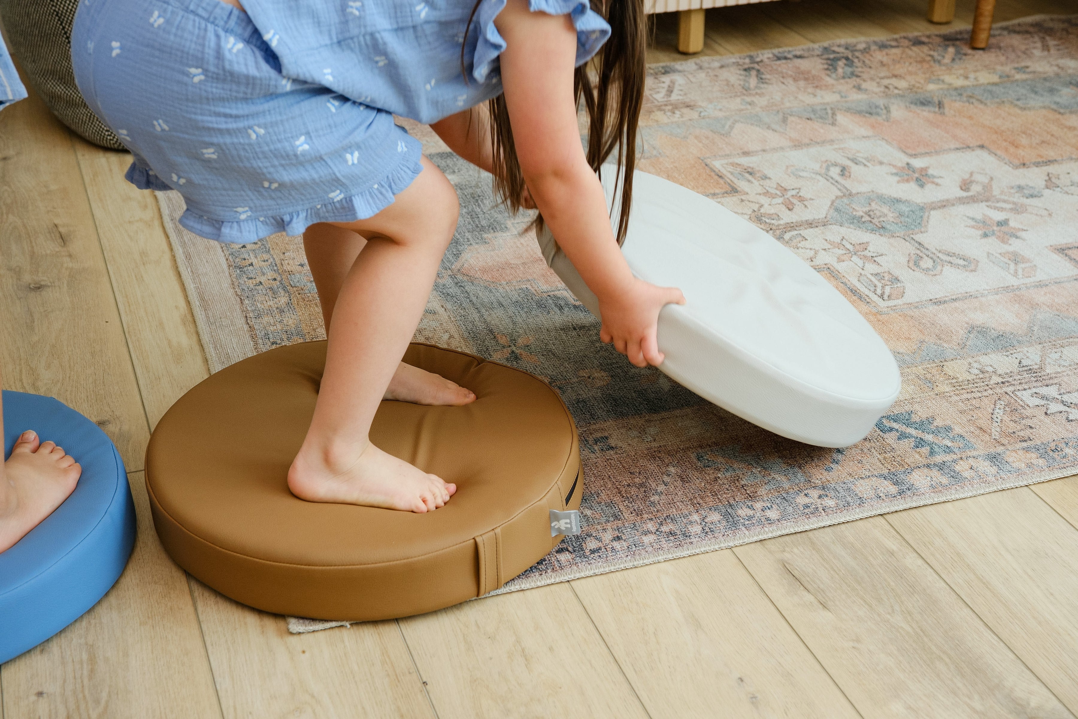 Child playing with  Foamnasium roundabout cushions on a wooden floor
