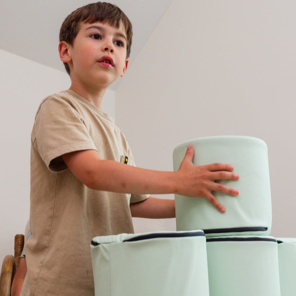 Child stacking Foamnasium Cylinders on top of each other in family room