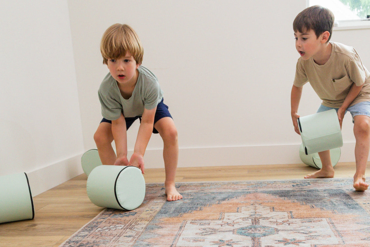 Two kids rolling Foamnasium Cylinders in living room