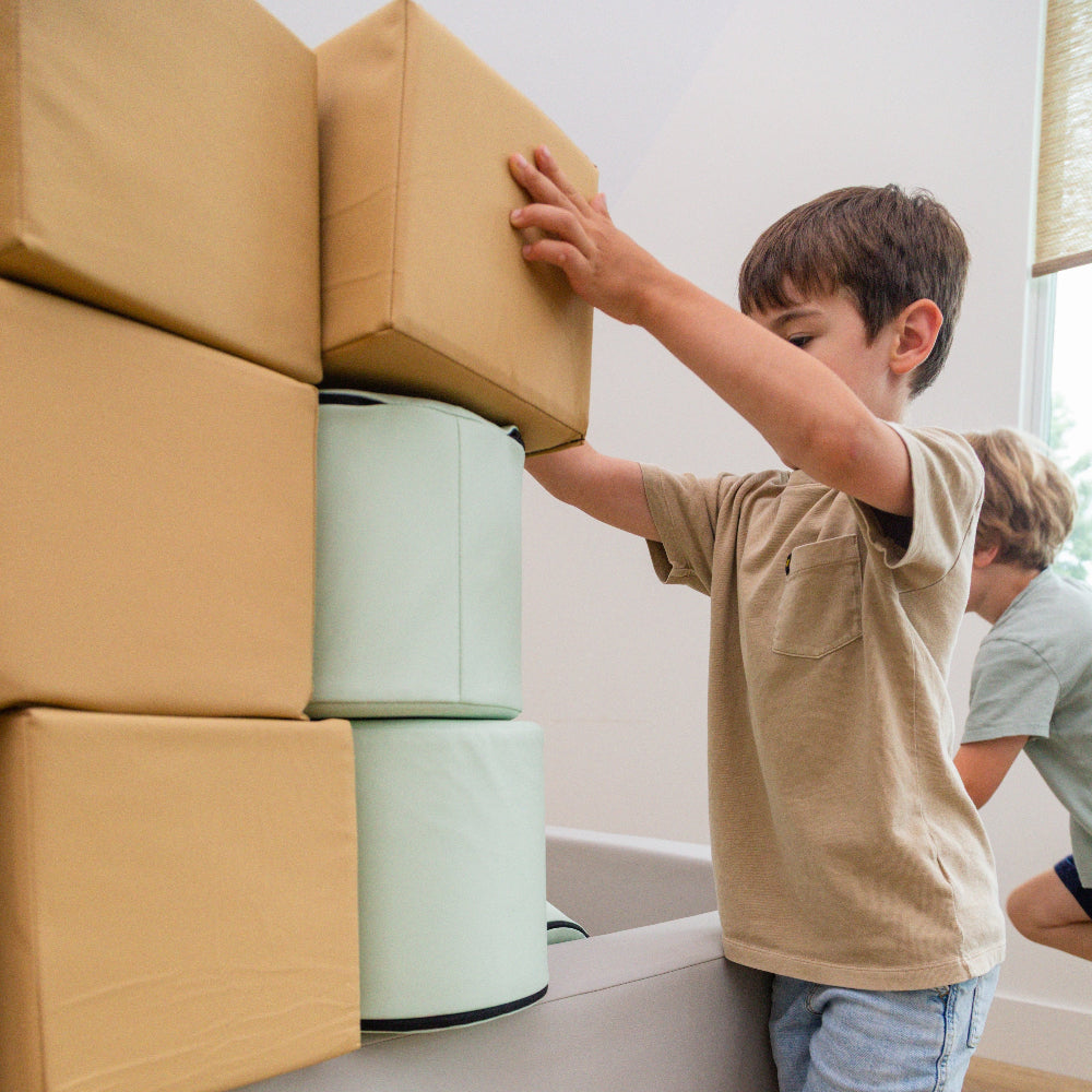 A child stacking Foamnasium cylinders on foam pit in living room