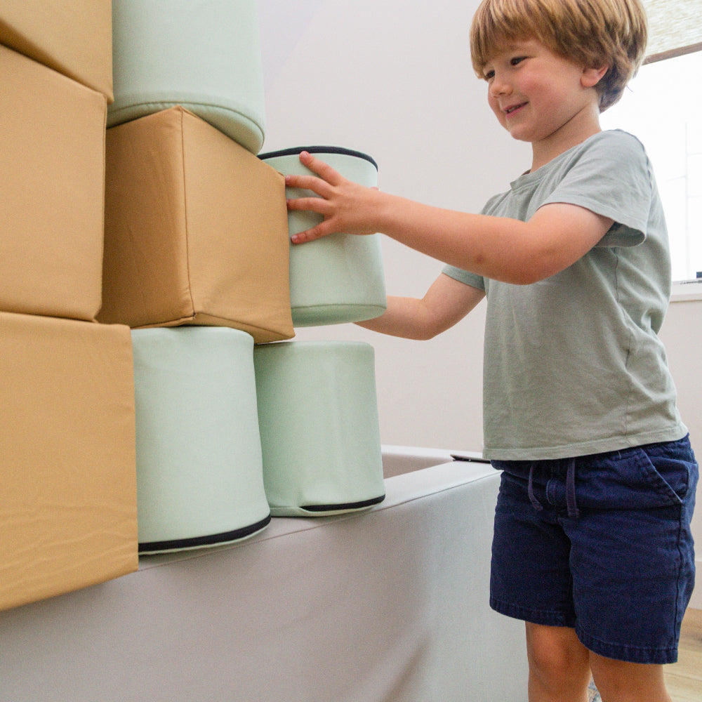 A child stacking Foamnasium Cylinders on a Foamnasium Foam Pit with cubes