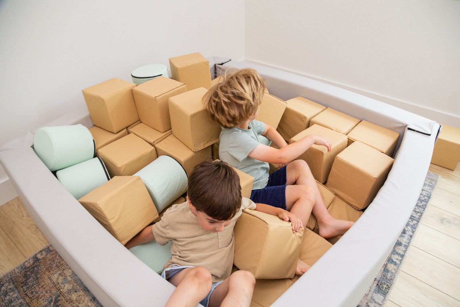 Two boys in Foam Pit with foam cutes and cylinders