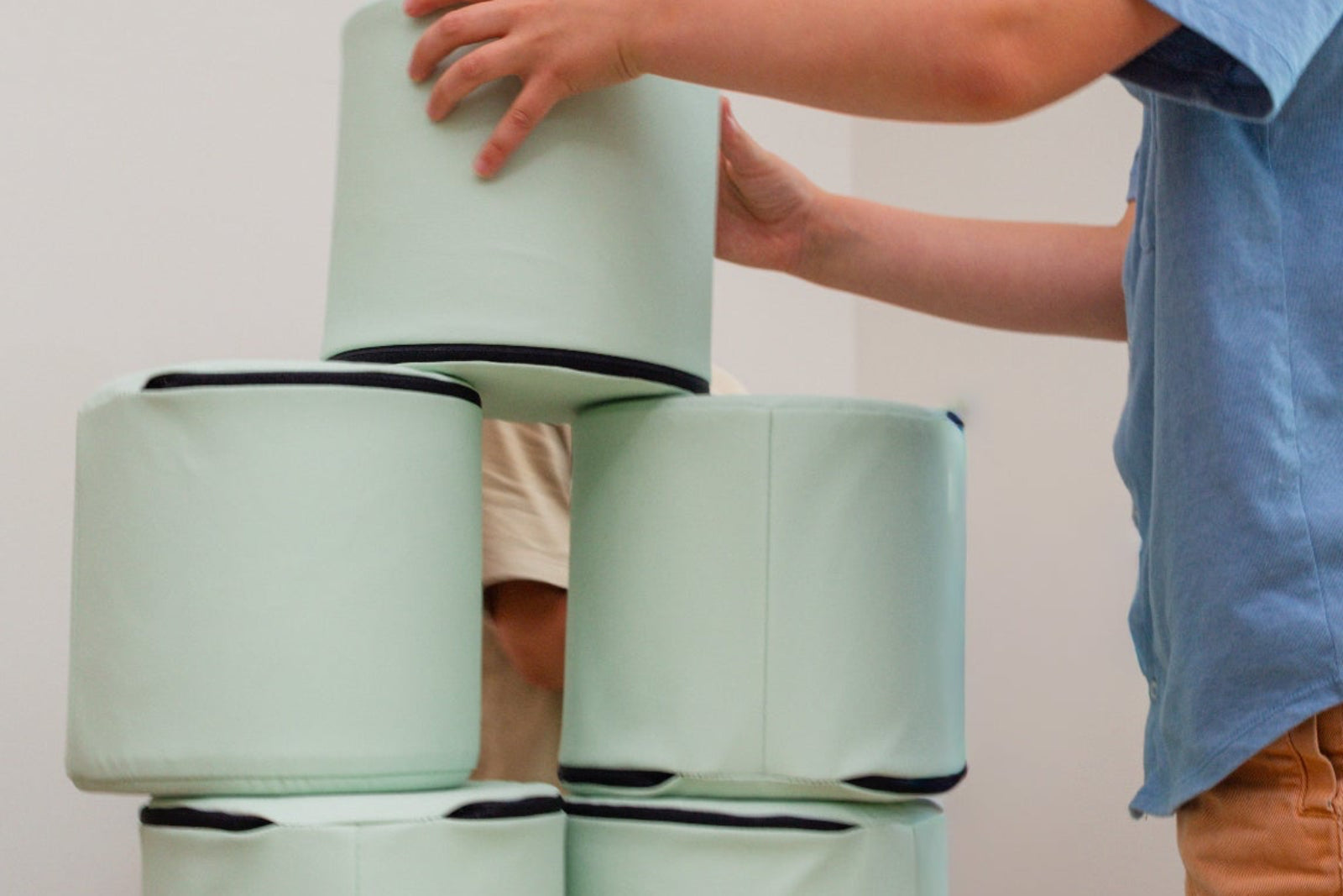 A older child stacking Foamnasium Cylinders in a living room