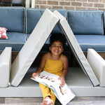 A photo of a girl sitting in a Gull Gray Blocksy set up as a tent