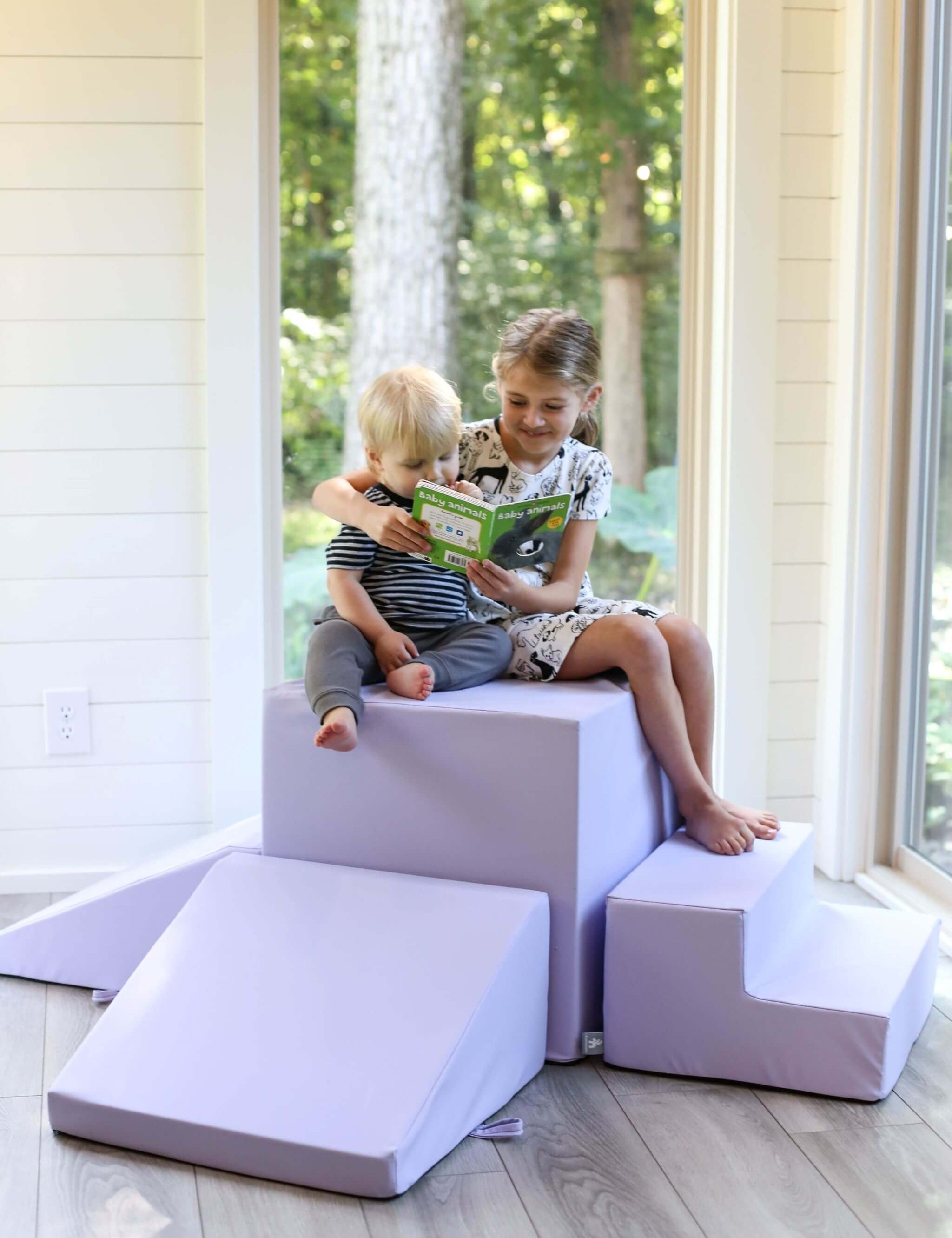 Lifestyle photo of a girl and a boy reading a book while sitting on a lavender gymnasium by Foamnasium