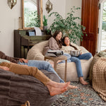 People relaxing on Haven bean bags in a cozy living room with plants and decor.