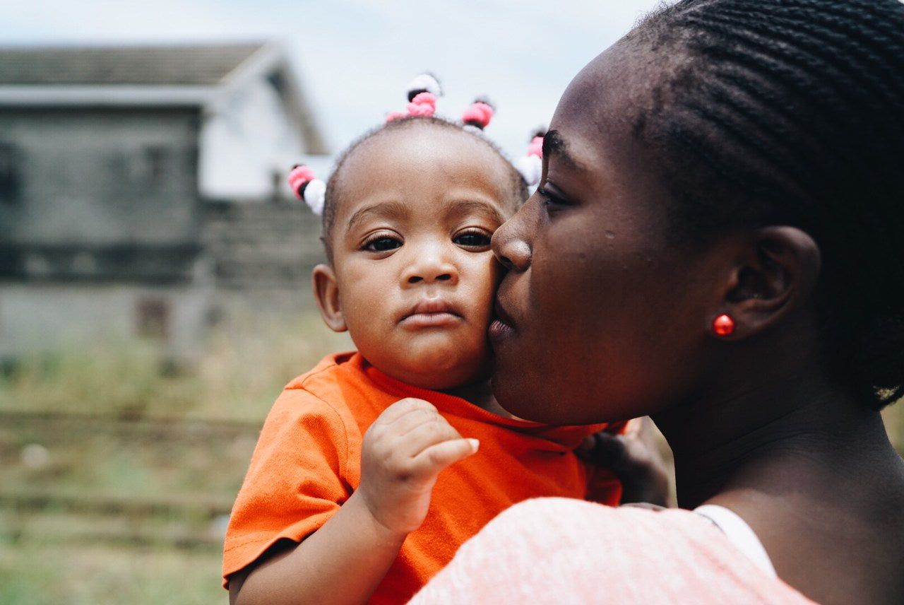 Picture from Foamnasium's partner, Mwana Villages, of a lady holding a baby looking happy