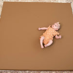 Baby lying on a Nutmeg Foamnasium mat on a patterned floor