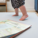 Child's feet standing on a yoga mat with a book open in front
