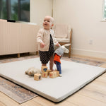 A little kid playing with toys on a Foamnasium mat