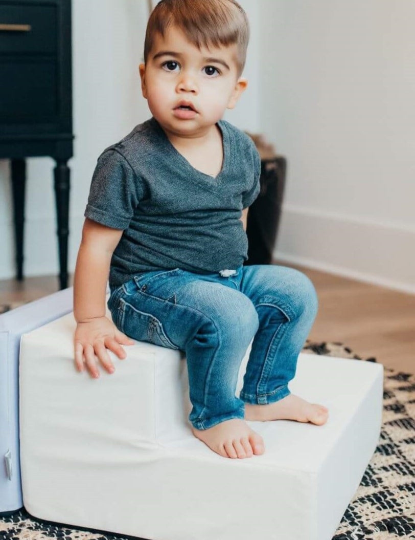 Lifestyle image of a boy sitting on an enhanced snow toddler step