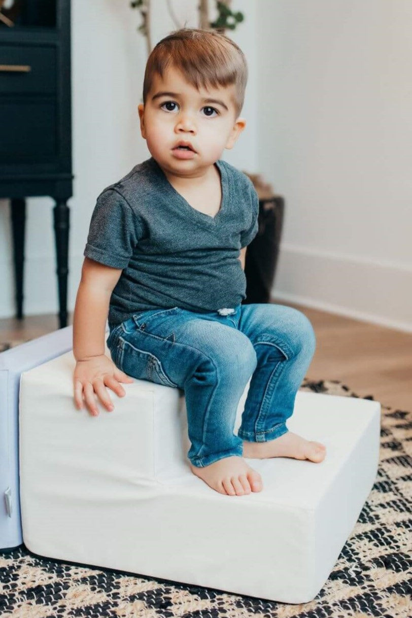 Lifestyle image of a boy sitting on an enhanced snow toddler step